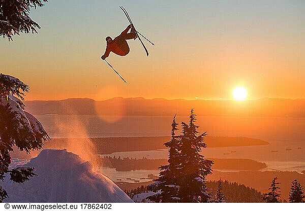 Skier Hitting a Jump at Sunset with City View