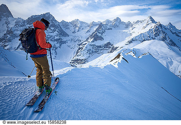 Skifahrer in orangefarbener Jacke auf Bergrücken
