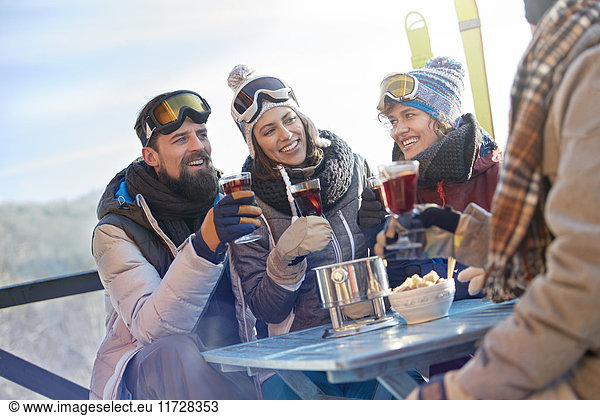 Skifahrerfreunde beim Trinken und Essen am Balkontisch Apres-Ski