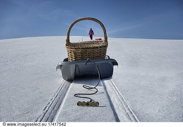Sled transporting picnic basket over hilly snowy winter landscape