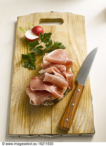 Slice of bread with ham on chopping board  close-up