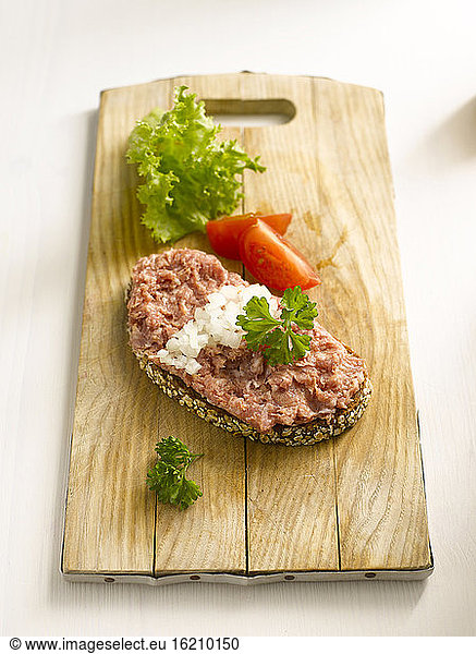 Slice of bread with minced meat on chopping board  close-up