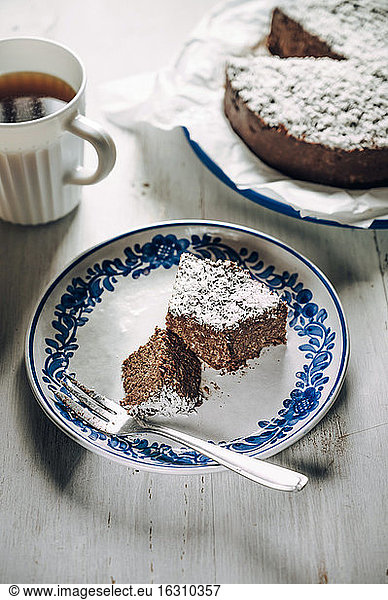 Slice of chocolate fridge tart with coconut shreds and mug of coffee