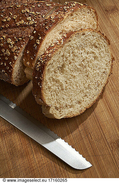 Slices of bread and knife on cutting board indoors