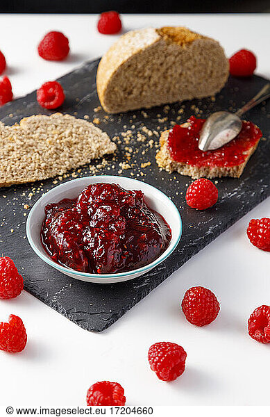 Slices of bread  fresh raspberries and bowl of raspberry jam