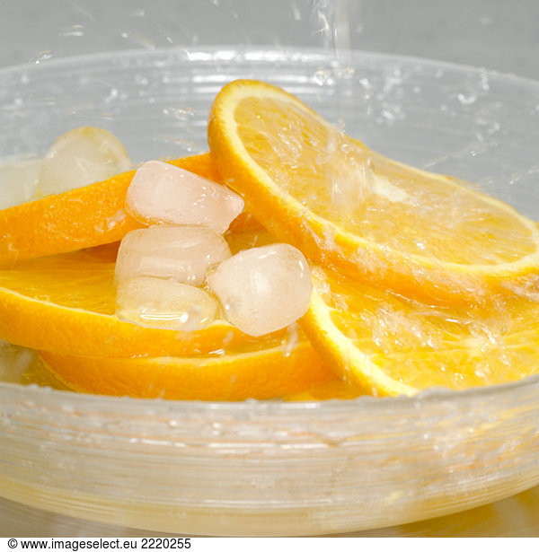 Slices of orange with ice cubes in bowl