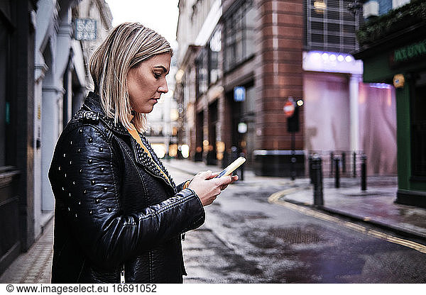 Slovak young woman using cellphone in city.