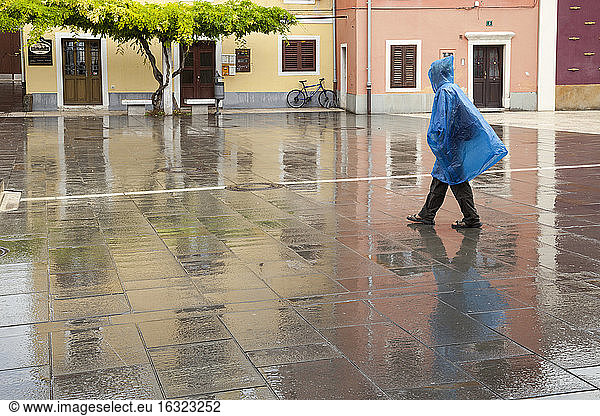Slovenia  Koper  woman with rain cape crossing Carpaccio Square