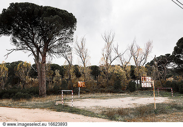 Small abandoned sports field with goals and basketball hoops