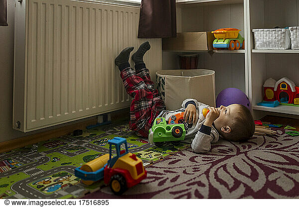 Small blonde boy in his room lying down on the floor and playing
