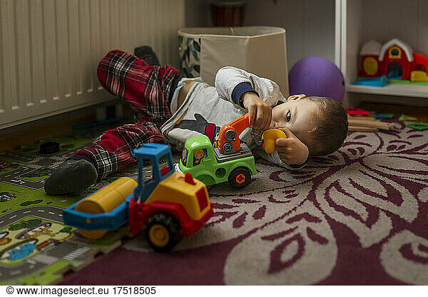 Small blonde boy in his room lying down on the floor and playing