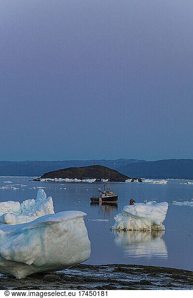 Small boat moored among large chunks of sea ice