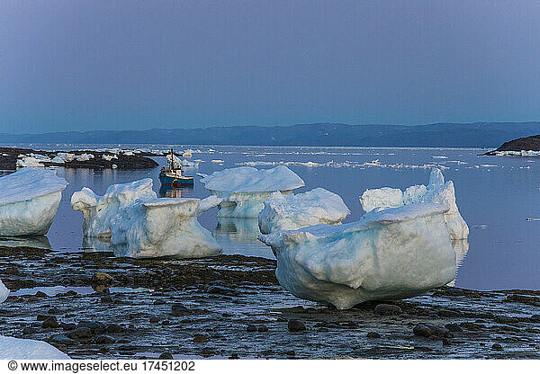 Small boat moored among large chunks of sea ice  Iqaluit  Canada.