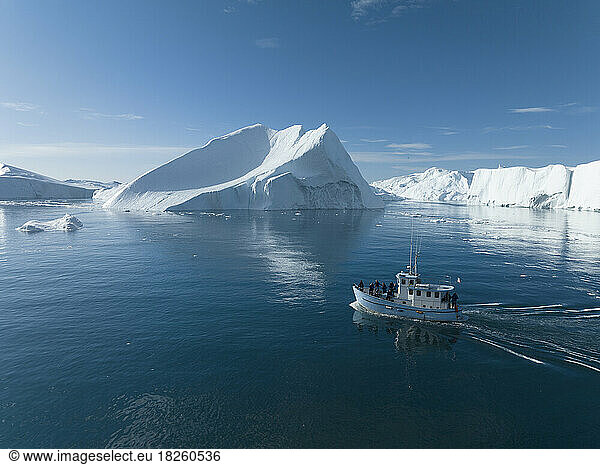 small boat near big icebergs from aerial point of view