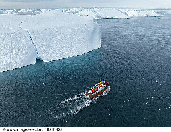 small boat near big icebergs from aerial point of view