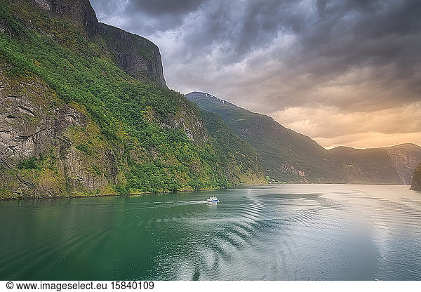 Small boat sailing in the amazing Norway fjords at sunset