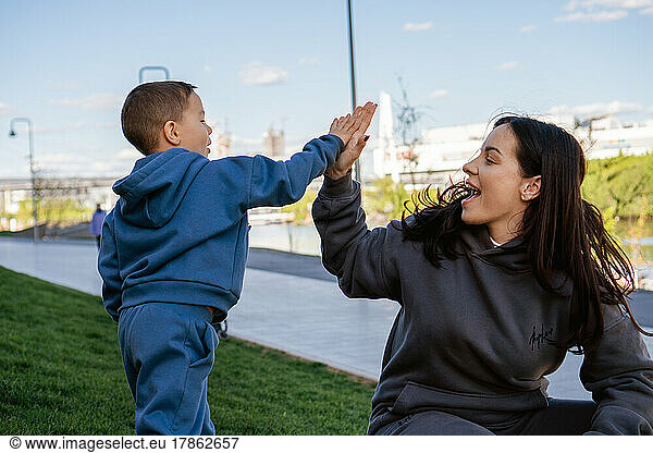 Small boy gives five young woman. Mother and son having fun outside.