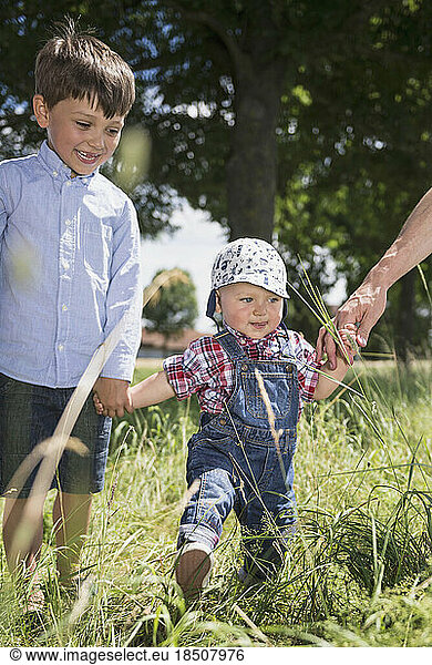 Small boy holding hand of his brother through a meadow in the countryside  Bavaria  Germany