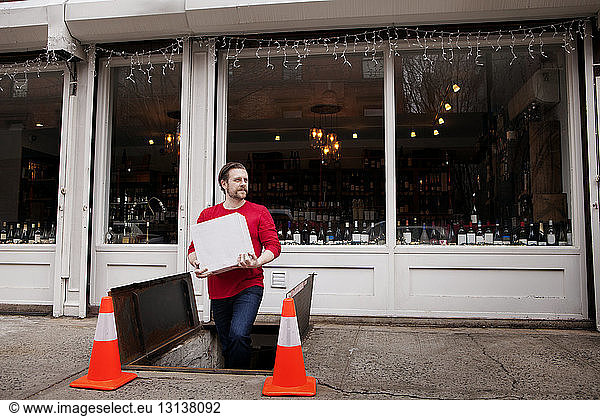 Small Business Owner holding package while exiting underground storehouse outside wine shop