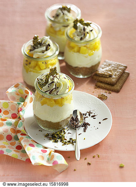 Small cheesecakes in a glass with mango cubes and cream