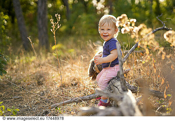 Small child laughing and sitting on a fallen tree