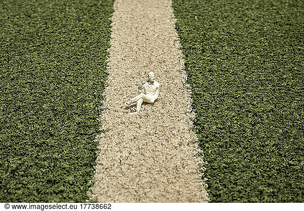 Small figurine lying on artificial grass of soccer field