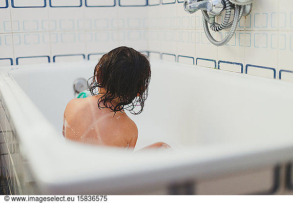 Small girl's back showering in bathtub