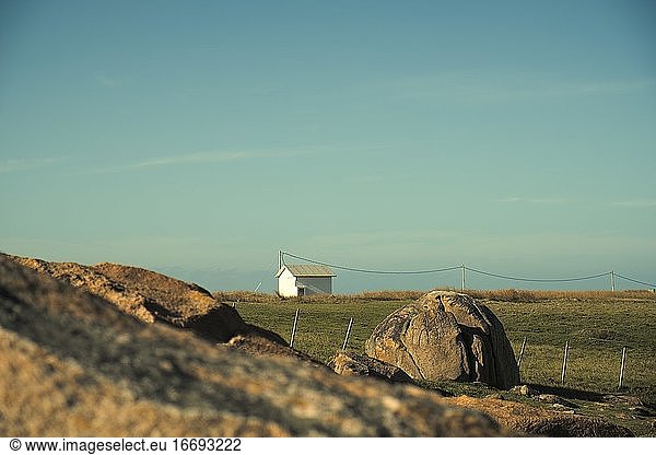 Small isolated house in a landscape with grass and rocks