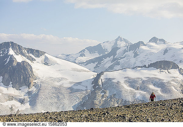Small man emerges over ridge crest in front of glacier
