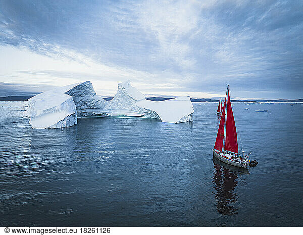 small sailboat near big icebergs from aerial point of view