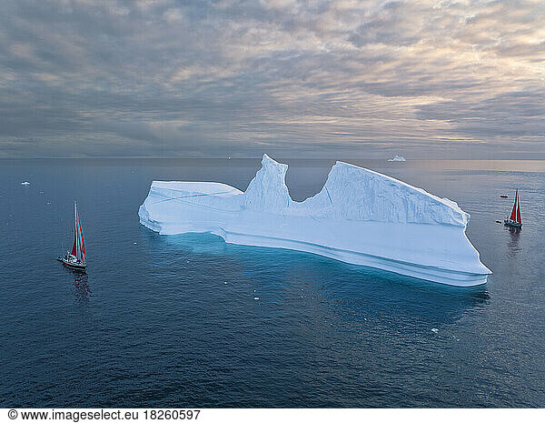 small sailboats near big icebergs from aerial point of view