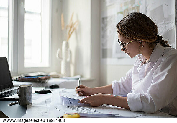 Smart businesswoman making notes on blueprint