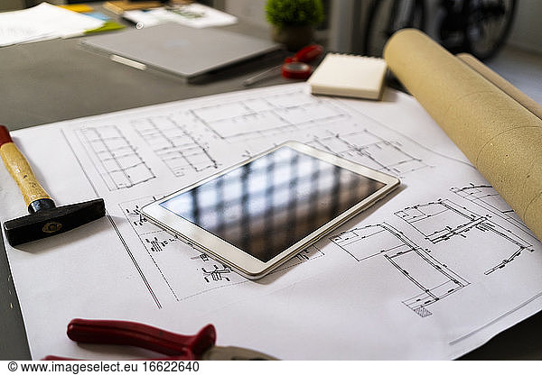 Smart phone and hammer lying on architectural blueprint