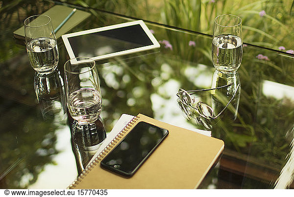 Smart phone and notebook on table with water glasses