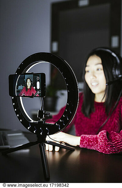 Smart Phone auf beleuchtetem Ringlicht gegen chinesische Vloggerin