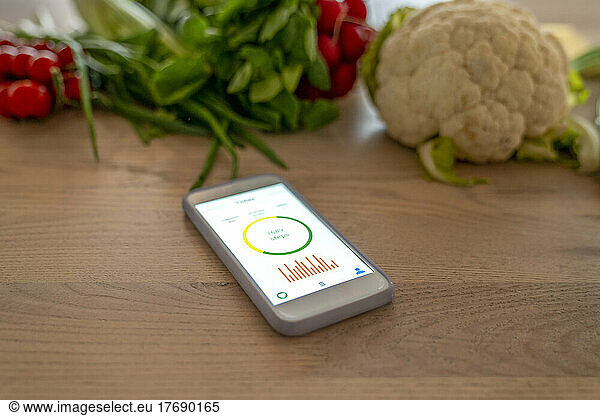 Smart phone with health tracker on device screen by vegetables