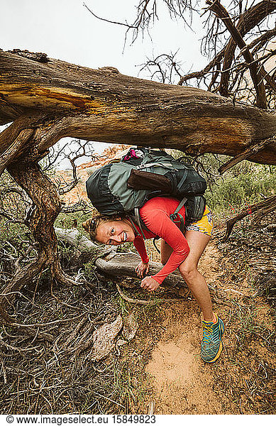 smiles all day for woman hiking in desert and ducking under dead tree