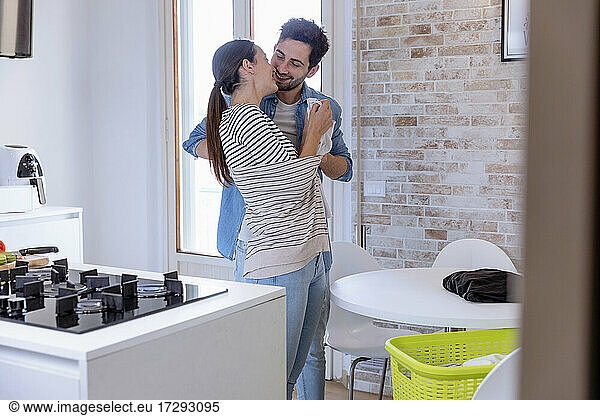 Smiling affectionate couple in domestic kitchen
