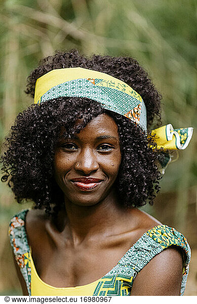 Smiling afro woman with african head band and colorful dress outdoor
