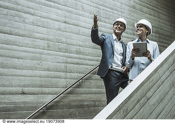Smiling architects having discussion on staircase