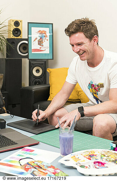 Smiling artist drawing on sketch pad while sitting at home
