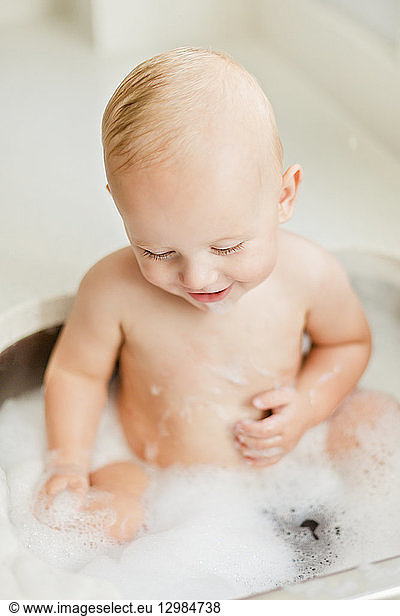 Smiling baby boy bathing in sink
