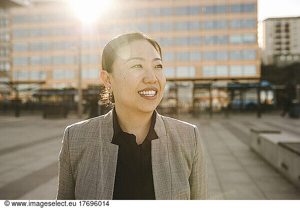 Smiling back lit businesswoman looking away on sunny day