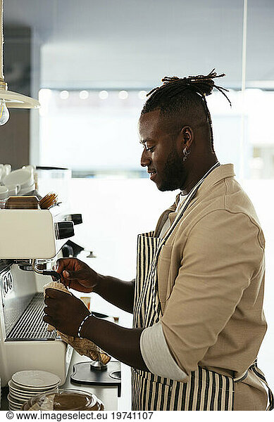 Smiling barista preparing coffee with machine at cafe
