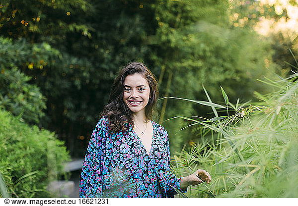 Smiling beautiful woman standing amidst plants in park