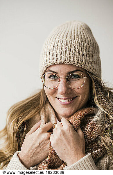 Smiling beautiful woman wearing warm clothing and eyeglasses against white background
