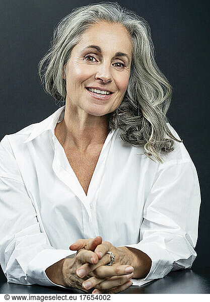 Smiling beautiful woman with gray hair against black background
