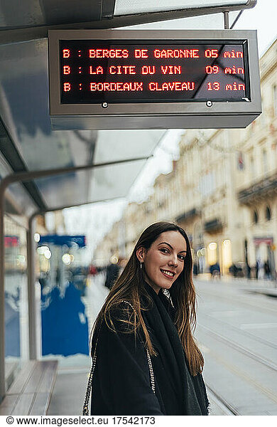 Smiling beautiful young woman waiting at tram station