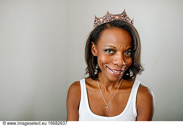 Smiling Black woman wearing tiara  tank top and cross necklace.
