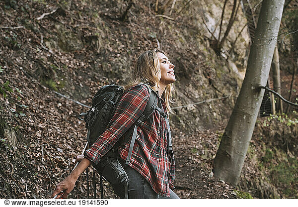Smiling blond backpacker exploring forest